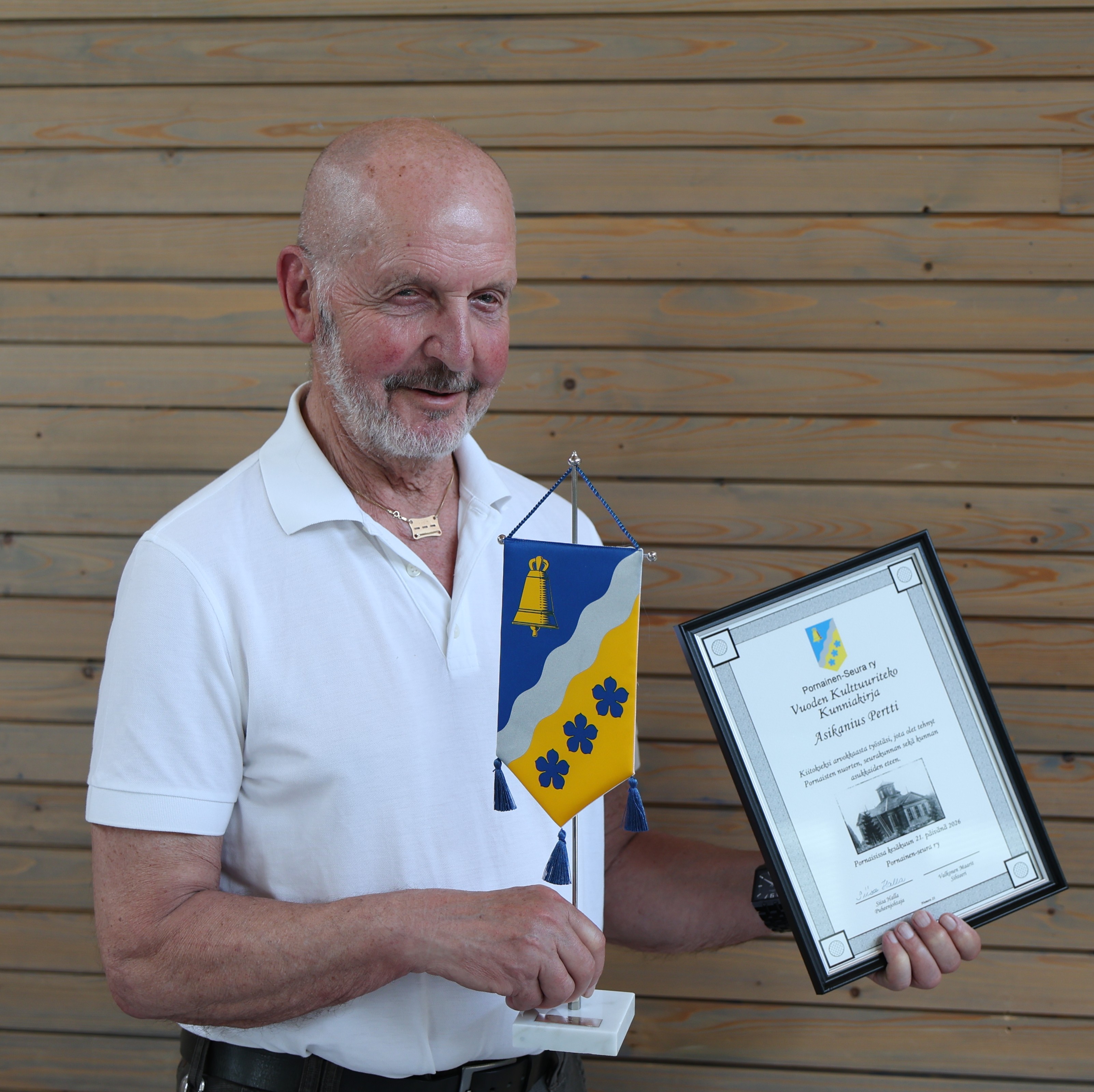 Pertti Asikanius pitämässä kunniakirjaa ja viiriä.